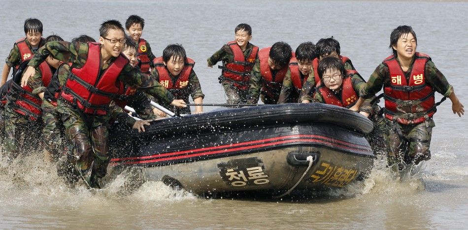 Elementary school students carry a rubber boat as they participate in a summer military camp for civilians at the Cheongryong Self-denial Training Camp run by retired marines in Ansan
