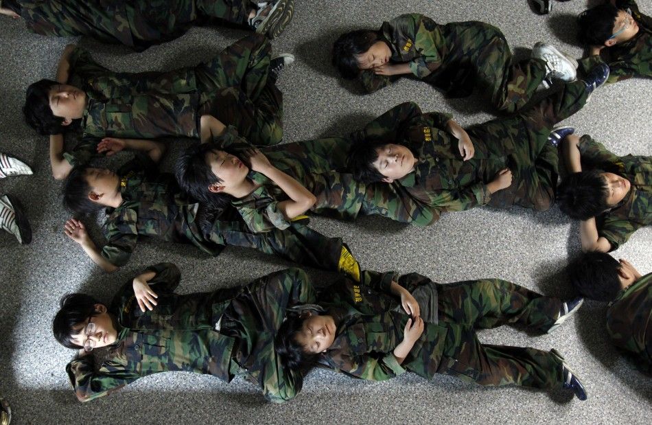 Elementary school students take a nap on a floor after a morning exercise as they participate in a summer military camp for civilians at the Cheongryong Self-denial Training Camp run by retired marines in Ansan