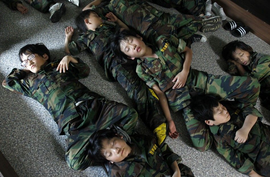 Elementary school students take a nap on a floor after a morning exercise as they participate in a summer military camp for civilians at the Cheongryong Self-denial Training Camp run by retired marines in Ansan