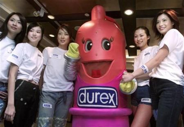 Models pose with a replica of a condom during the 2001 Durex Global Sex Survey Press conference in Hong Kong