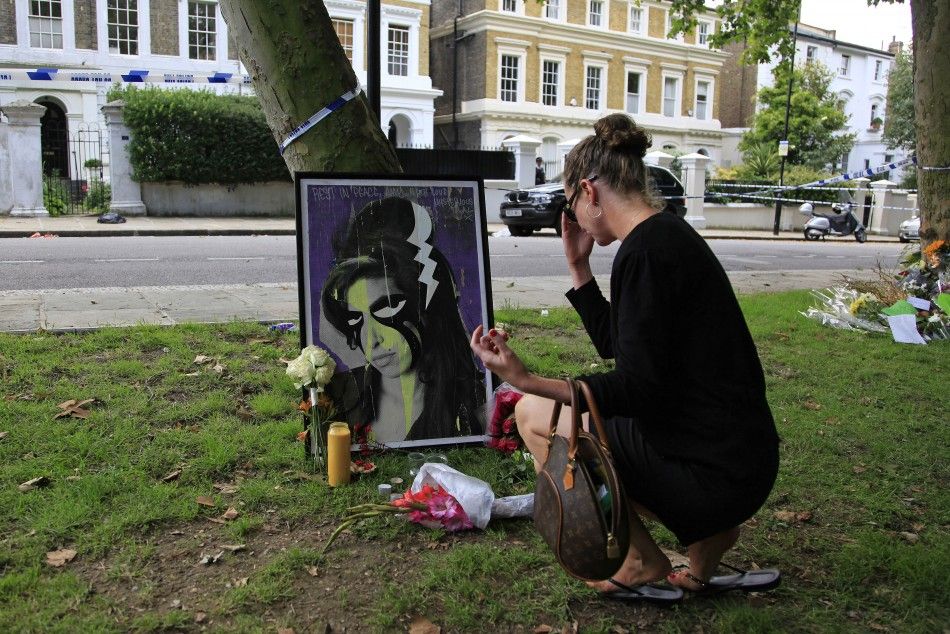A woman leaves flowers outside the home of Amy Winehouse in London