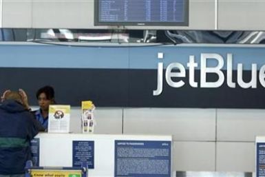 A JetBlue employee assists a customer at the check-in counter at JFK International Airport in New York