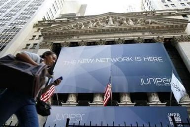 A woman walks past a banner with the logo of Juniper Networks Inc. covering the facade of the New York Stock Exchange