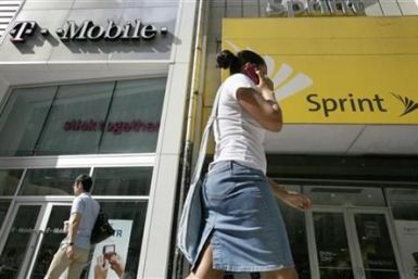 A woman talks on her phone as she walks past T-mobile and Sprint wireless stores in New York