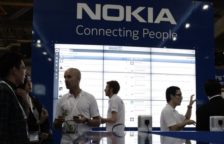 Staff members speak to trade visitors at the Nokia booth at the CommunicAsia expo in Singapore