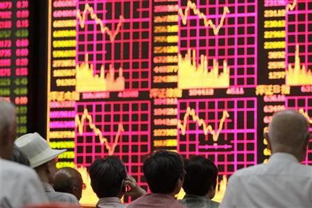 People look at an electronic board at a brokerage house in Shanghai