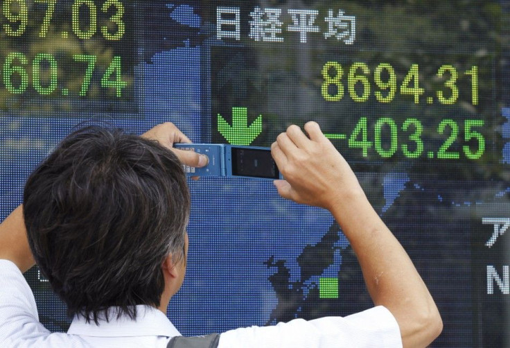 A man takes a picture of a stock index board with his mobile phone outside a brokerage in Tokyo