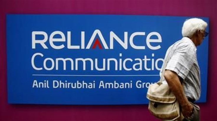 A man walks past a logo of Reliance Communication before Annual General Meeting in Mumbai