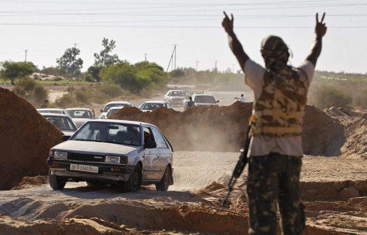 A Libyan rebel fighter raises his arms as a convoy of residents flee fighting near the coastal town of Zawiyah