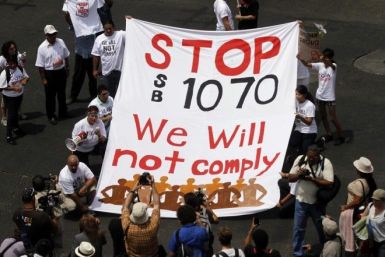 Demonstrators hold a banner as they protest against Arizona's controversial Senate Bill 1070 immigration law outside the U.S. District Court in Phoenix July 22, 2010. 