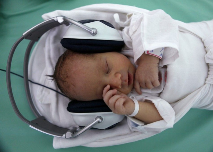 A newborn baby rests in a box, listening to music played through earphones in Saca Hospital in Kosice