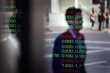 Man is reflected in a window as he walks past the indicator boards at the Australian Stock Exchange in Sydney