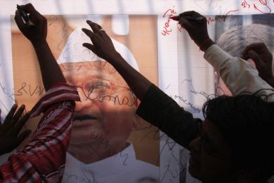 Supporters of Anna Hazare sign a banner with a portrait of Hazare outside the Tihar jail in New Delhi