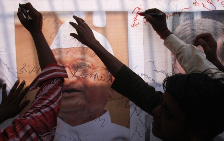 Supporters of Anna Hazare sign a banner with a portrait of Hazare outside the Tihar jail in New Delhi