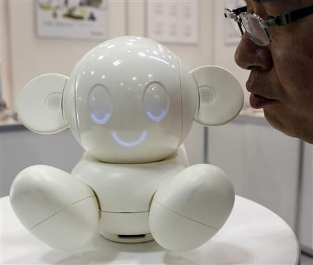 A man talks to Raytron's communication robot 'Chapit' at a demonstration during ROBOTECH, an exhibition on service robot manufacturing technologies, in Tokyo