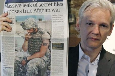 Wikileaks founder Julian Assange holds up a copy of a newspaper during a press conference .