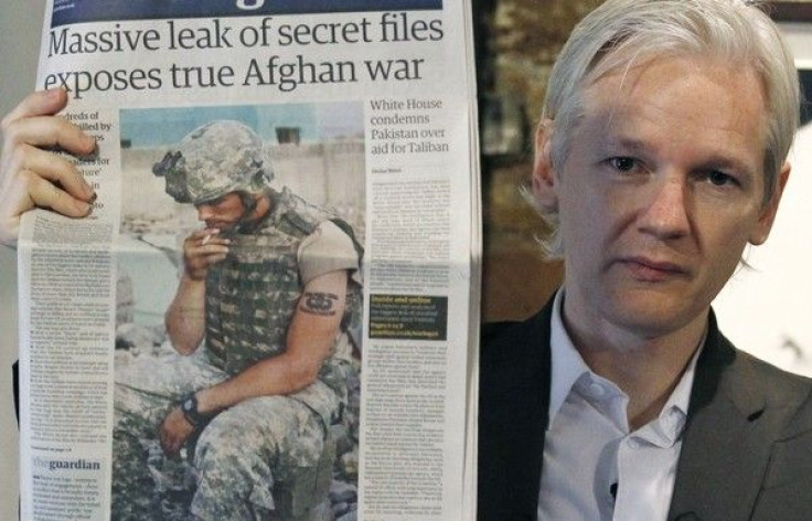 Wikileaks founder Julian Assange holds up a copy of a newspaper during a press conference .