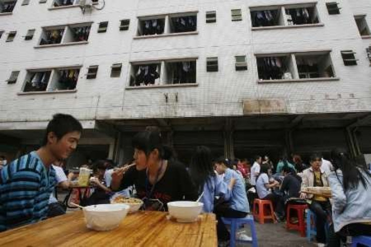Migrant workers eat their lunch outside a dormitory building at a factory district in the southern Chinese city of Shenzhen in Guangdong province