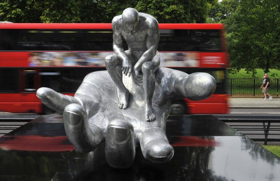 A double-decker bus passes the quotHand of Godquot sculpture by Italian artist Lorenzo Quinn in central London