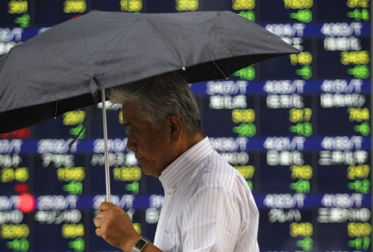 A man walks past an electronic board displaying share prices in Tokyo