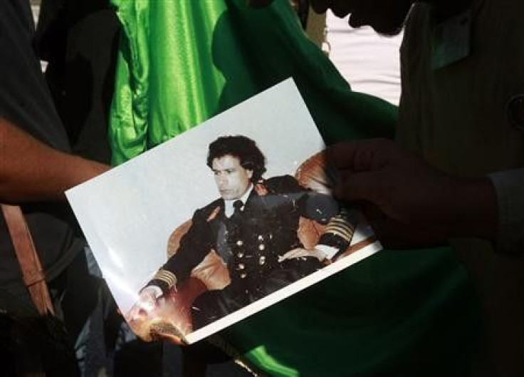 Libyan rebel fighters burn a picture of Muammar Gaddafi at a checkpoint in Tripoli&#039;s Qarqarsh district