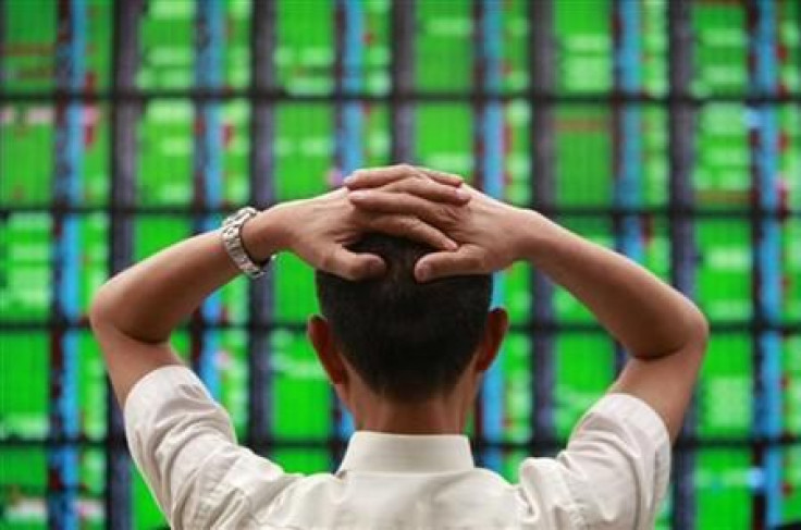 A man looks at a display board showing stock market prices inside a brokerage in Taipei