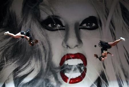 Cheerleaders jump in front of a Lady Gaga poster before a welcoming ceremony inside the Taichung City Hall building, central Taiwan