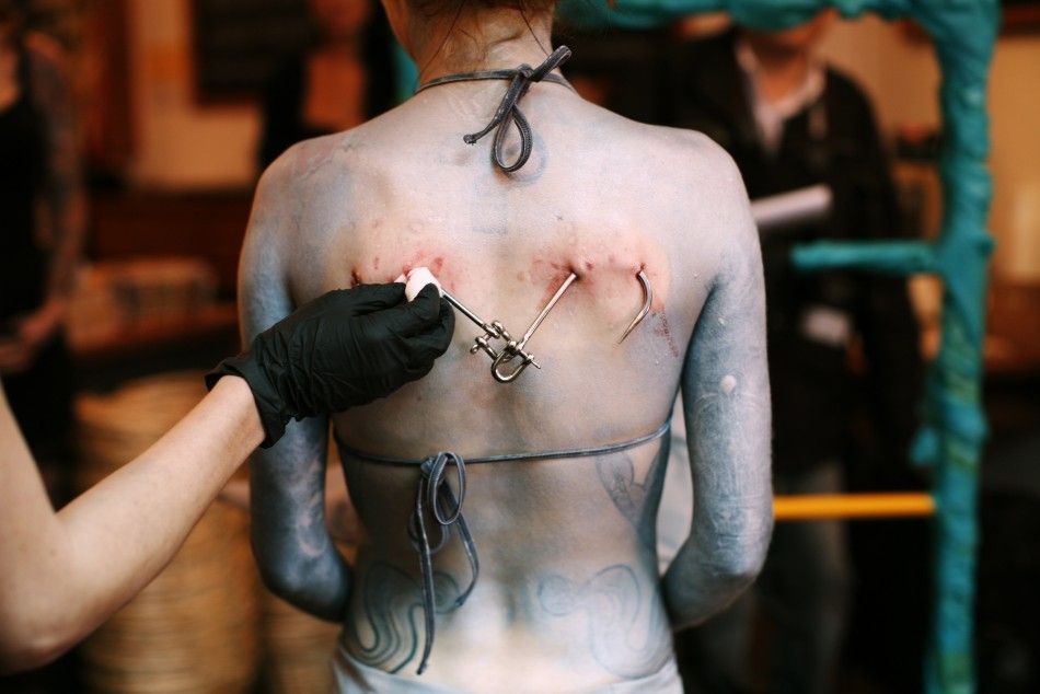 Blood is wiped from the back of British performance artist Alice Newstead after she was suspended from shark hooks at a cosmetic shop in San Francisco
