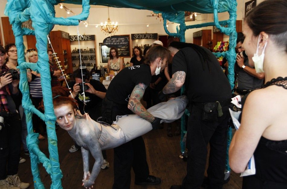 British performance artist Alice Newstead prepares to be suspended from shark hooks at a cosmetic shop in San Francisco