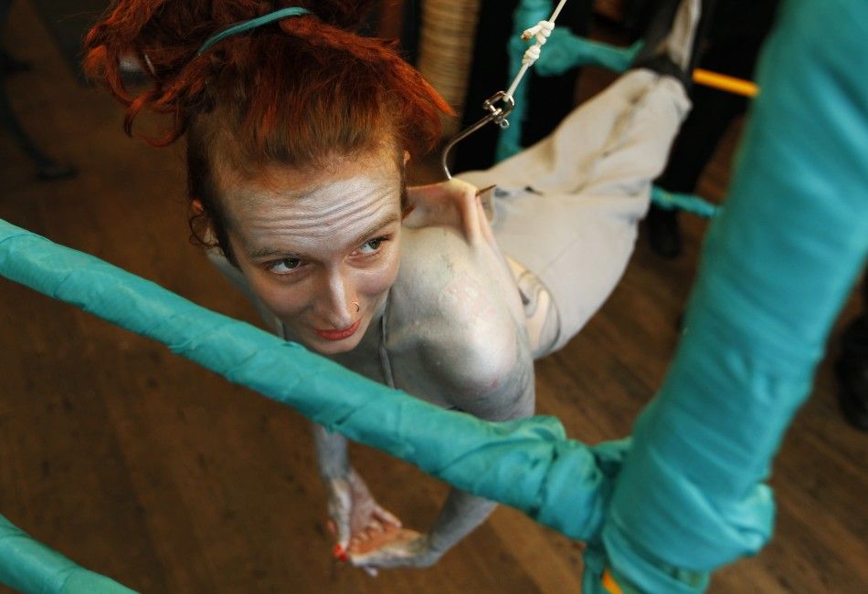 British performance artist Alice Newstead suspends from shark hooks pierced through her back at a cosmetic shop in San Francisco