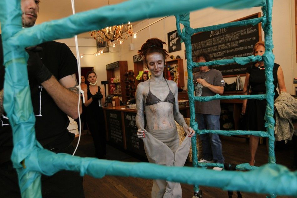British performance artist Alice Newstead approaches a stand prior to being suspended from shark hooks at a cosmetic shop in San Francisco