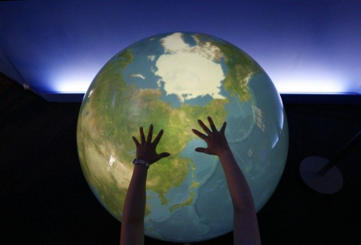 A visitor places her hands on a tangible earth, a digital globe, at an exhibition pavillion in Rusutsu town, northern Japan.