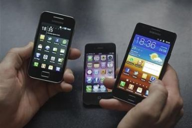 A man holds a Samsung S II and Samsung Ace smartphones next to an Apple iPhone 4 in Houten