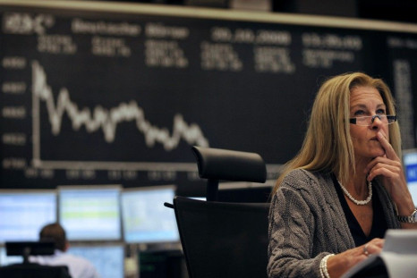 A share trader checks share prices as she sits behind her trading terminals at the trading floor of the German stock exchange in Frankfurt