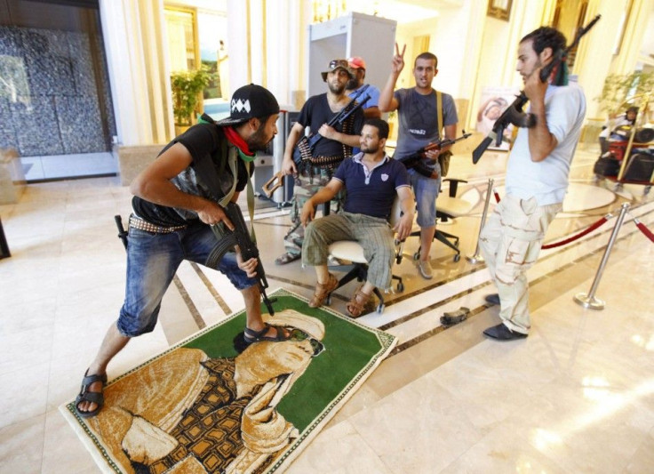 A rebel steps on a poster of Libya&#039;s leader Muammar Gaddafi at Rixos hotel in Tripoli