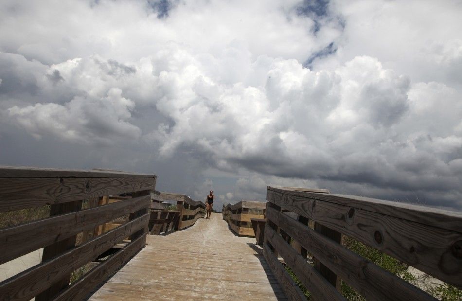Storm clouds loom as a beachcomber walks on a beach access ramp on the west end of Sunset Beach, North Carolina