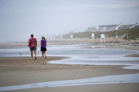 Visitors walk along the beach at high tide the day before the expected landfall of Hurricane Irene in Atlantic Beach