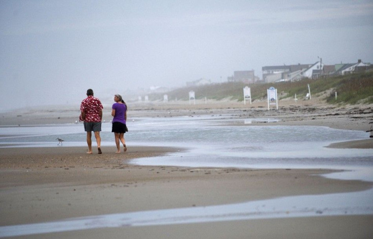 Visitors walk along the beach at high tide the day before the expected landfall of Hurricane Irene in Atlantic Beach