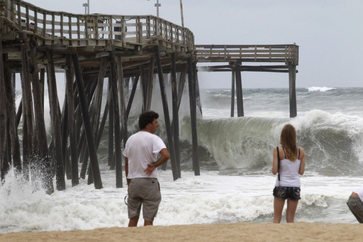 Residents look on as waves hit the pier at Cape Hatteras National Seashore in Avon, North Carolina 