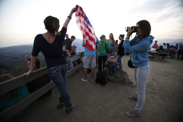 A woman holds a U.S. flag while posing for a photo as she waits for Independence Day fireworks in Los Angeles