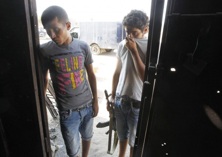 Rebel fighters look inside a warehouse at burnt bodies at the Khamis 32 military encampment in southern Tripoli