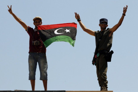 Rebel fighters show victory signs as they hold a Kingdom of Libya flag at the Tunisan border post of Ras Jdir