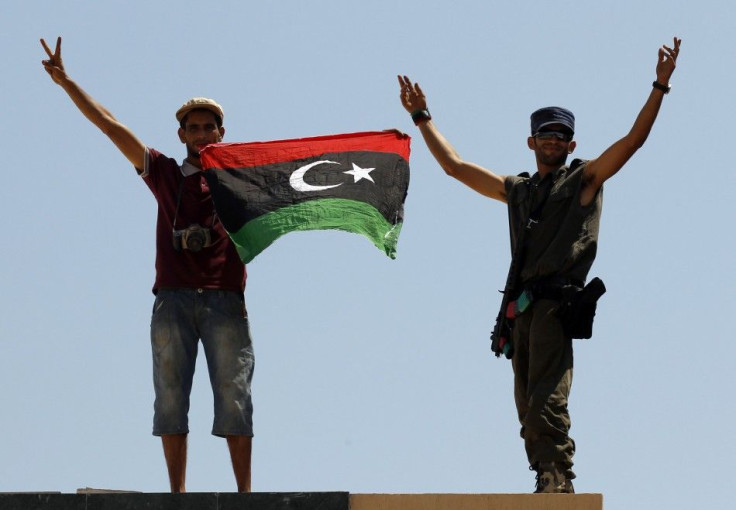 Rebel fighters show victory signs as they hold a Kingdom of Libya flag at the Tunisan border post of Ras Jdir