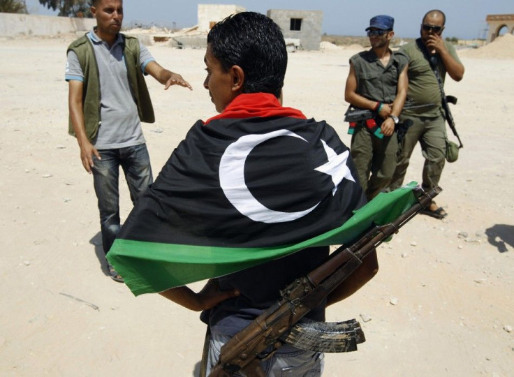 Libyan rebels, one wearing a Kingdom of Libya flag, walk around the Ras Jdir border post on the border with Tunisia