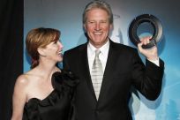 Cast member Boxleitner holds an Identity Disc as he poses with his wife Gilbert at the world premiere of the film &quot;TRON: Legacy&quot; in Hollywood