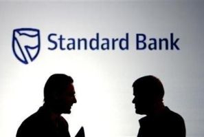 Businessmen chat in front of a Standard Bank logo in Sandton outside Johannesburg