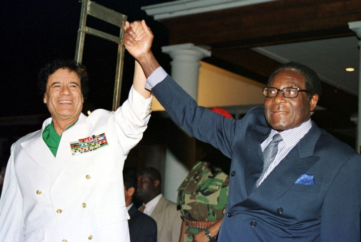 Libyan leader Colonel Muammar Gadaffi (L) and Zimbabwe President Robert Mugabe greet supporters outside State House in Harare July 12, 2001.