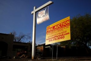 A realtor and bank-owned sign is displayed near a house for sale in Phoenix