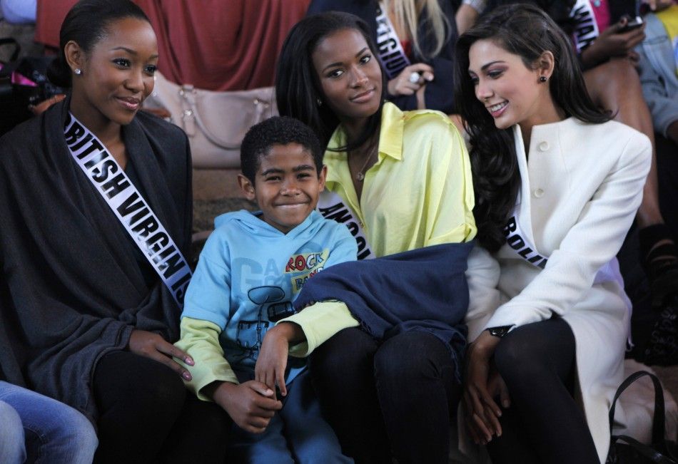 Miss Bolivia 2011 Olivia Pinheiro R, Miss Angola 2011 Leila Lopes and Miss British Virgin Islands 2011 Sheroma Hodge L pose for a photograph with a children at Alianca Misericordia non-profit catholic organization in the outskirts of Sao Paulo