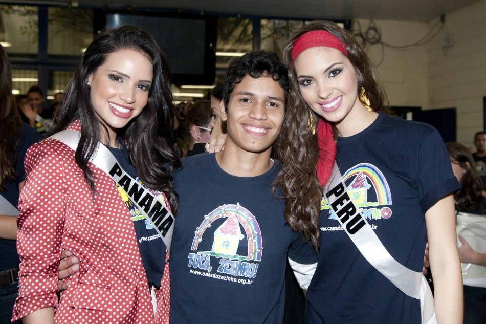 Miss Panama Sheldry Saez and Miss Peru Natalie Vertiz pose with a boy at Casa Do Zezinho social project for slum children, in Sao Paulo